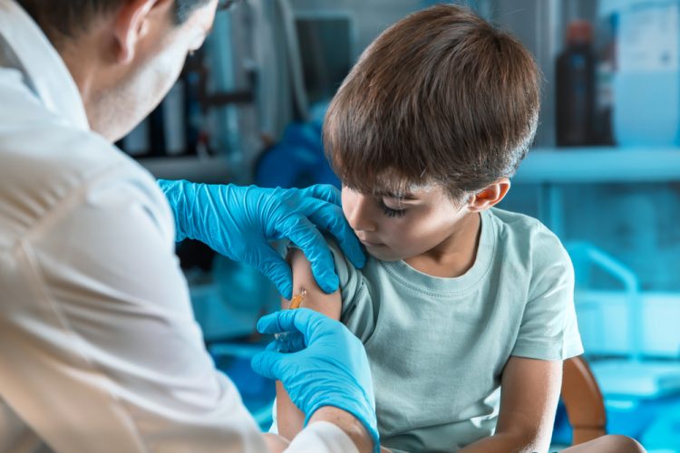 Young male child recieving an injection from a doctor in his upper arm