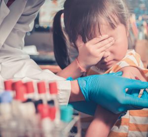 little girl covering her eyes as she is injected by doctor