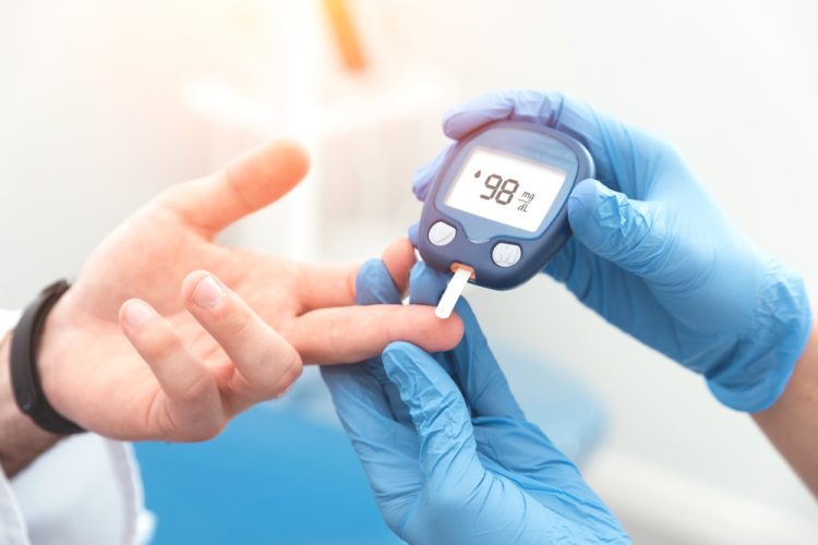 Diabetes patient's blood glucose level being checked by doctor