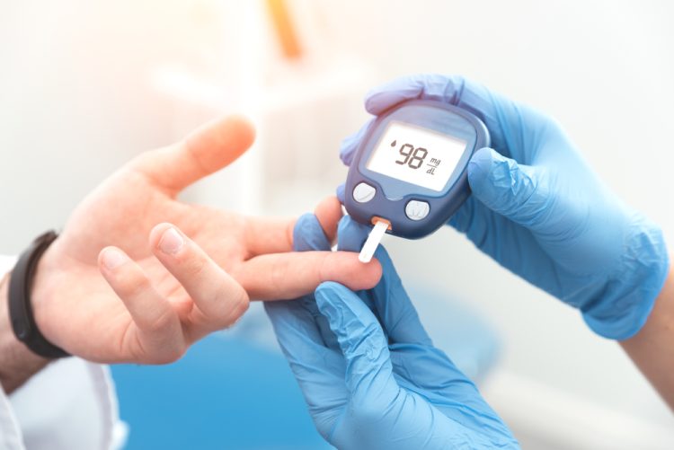 Diabetes patient's blood glucose level being checked by doctor