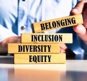 Wooden blocks with words 'equity, diversity, inclusion, belonging' being stacked by a businessman