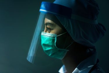 Profile of a doctor wearing a gown, mask, face shield and hair net - idea of personal protective equipment