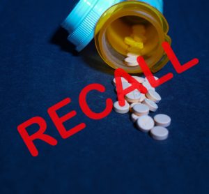 Tablets spilling from a yellow pill bottle with the word recall over the top - idea of a drug recall