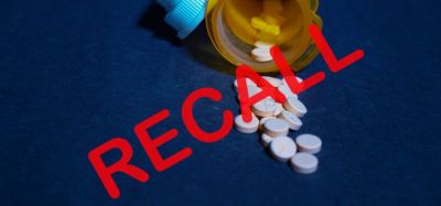 Tablets spilling from a yellow pill bottle with the word recall over the top - idea of a drug recall