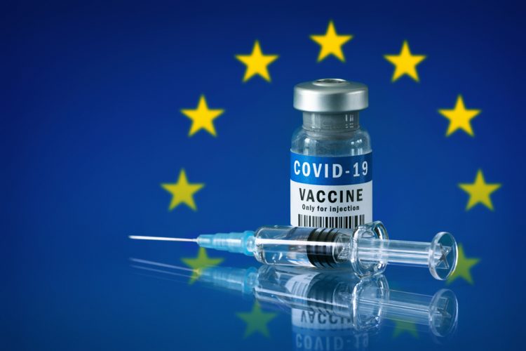 Vial labelled 'COVID-19 VACCINE' with a syringe in front of the EU flag (Blue with a central circle of gold stars)