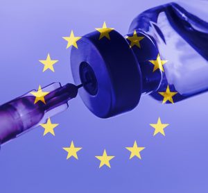 Syringe drawing a vaccine dose from a vial overlaid with the EU flag (blue with central circle of golden stars)