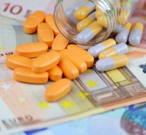 Concept of EU Drug pricing or cost of goods - Pills and capsules scattered from a bottle on euro banknotes