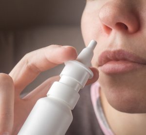 women holding nasal spray to her nose
