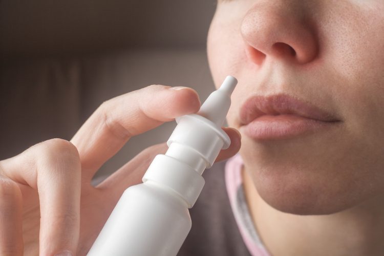 women holding nasal spray to her nose