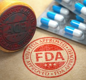 Stamp reading 'FDA APPROVED' next to a stack of blue and white capsules in blister packaging