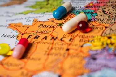 Pills laying on top of a map of France in an atlas