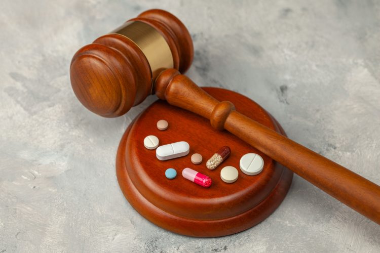 Wooden Judge's gavel and pills - idea of pharmaceutical regulations such as France's temporary authorisation (ATU) Programme