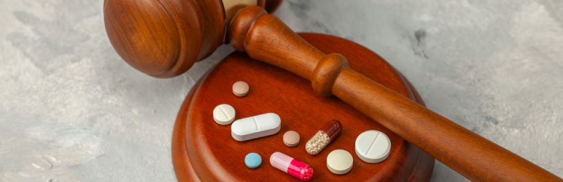 Wooden Judge's gavel and pills - idea of pharmaceutical regulations such as France's temporary authorisation (ATU) Programme