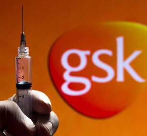 GSK logo (orange rounded corner inverted triangle with GSK lettering in white) with a gloved hand holding a syringe in front - idea of GSK vaccines