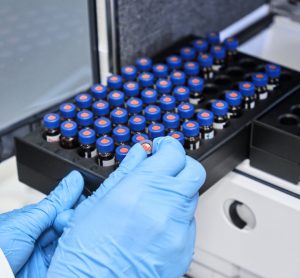 Close up of chemist putting vials of samples into autosampler of HPLC system.