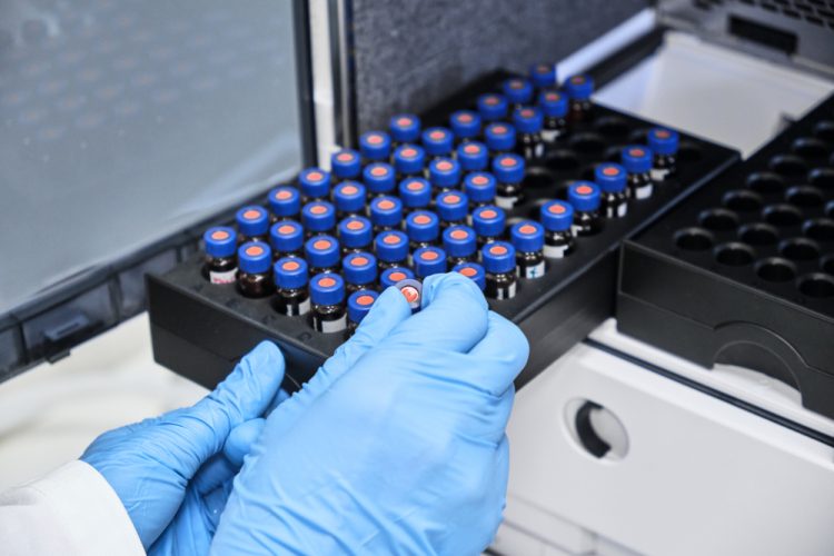 Close up of chemist putting vials of samples into autosampler of HPLC system.