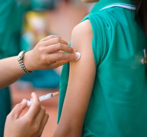 young girl receiving a vaccine from a volunteer