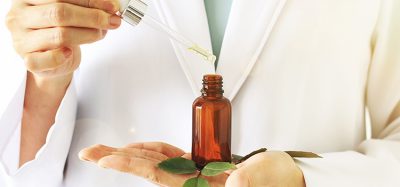 Idea of herbal/plant-based medicine: scientist holding a dropper and amber vial