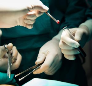 Surgeons transferring tissue sample into test tube