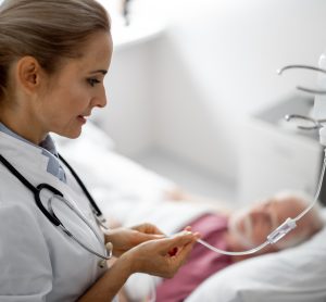 doctor checking IV line of an elderly patient in a hospital bed