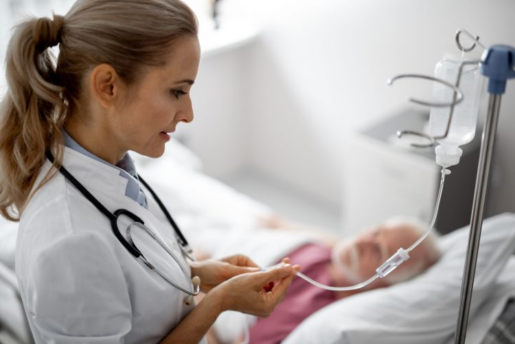 doctor checking IV line of an elderly patient in a hospital bed