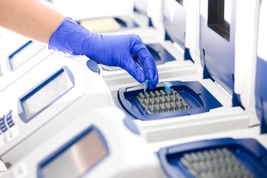 Scientist placing specimen tube into a Real-time PCR cycle - idea of PCR testing for COVID-19