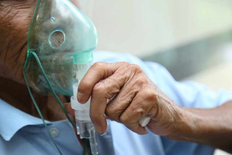Elderly male patient wearing an oxygen mask - idea of respiratory distress/inhaled drug delivery