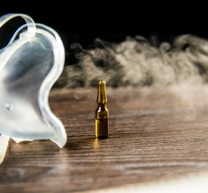 mist coming from a nebuliser surrounding a brown vial - idea of inhaled treatment or vaccine