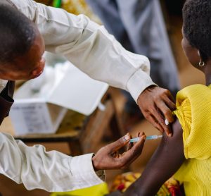 Male doctor injecting a woman in the upper arm with a syringe in Africa