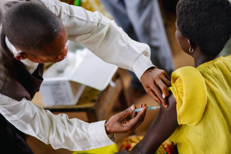 Male doctor injecting a woman in the upper arm with a syringe in Africa