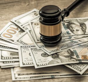 Wooden gavel on top of a stack of US 100 Dollar bills - idea of legal settlement