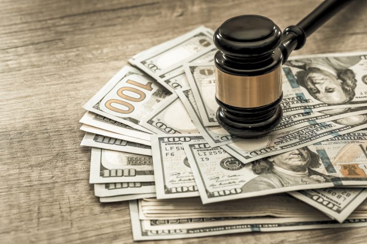 Wooden gavel on top of a stack of US 100 Dollar bills - idea of legal settlement