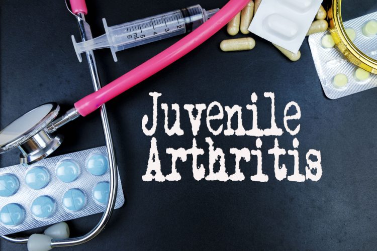 Words 'Juvenile Arthritis' surrounded by medicines and a stethoscope - idea of treatments for juvenile arthritis