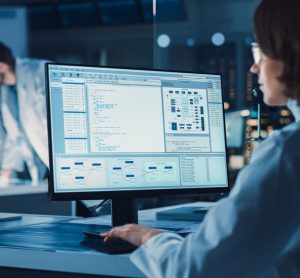 Over the Shoulder Shot: Female Scientist in lab Using Computer showing laboratory information management system or process control system