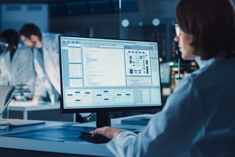 Over the Shoulder Shot: Female Scientist in lab Using Computer showing laboratory information management system or process control system