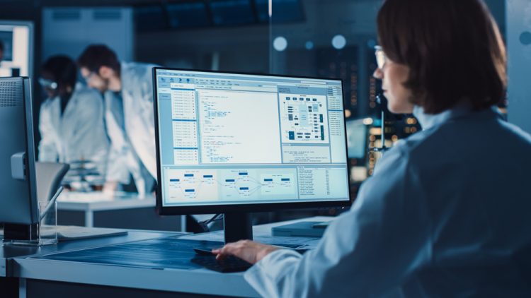 Over the Shoulder Shot: Female Scientist in lab Using Computer showing laboratory information management system or process control system