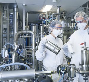 Two pharma manufacturing plant workers surrounded by equipment