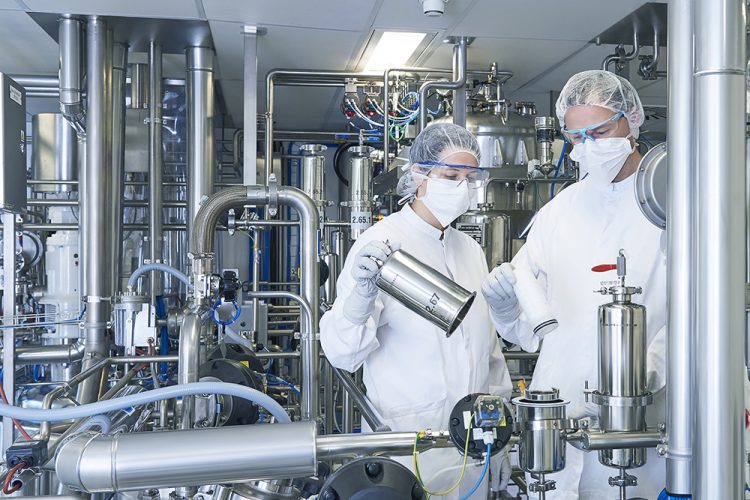 Two pharma manufacturing plant workers surrounded by equipment