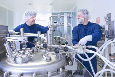 male manufacturing plant workers surrounded by metal equipment