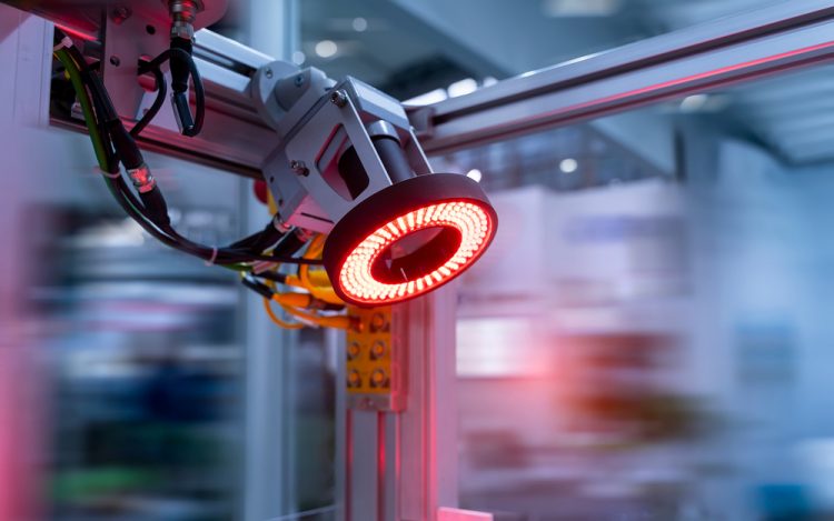 Photo of a glowing red machine vision camera in an advanced industry production line - idea of process analytical technologies (PAT)