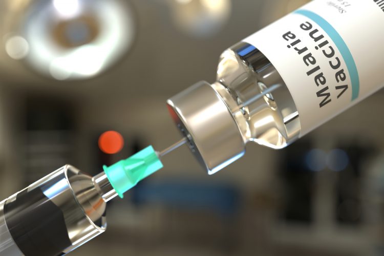 Syringe drawing clear liquid from a vial labelled 'MALARIA VACCINE'