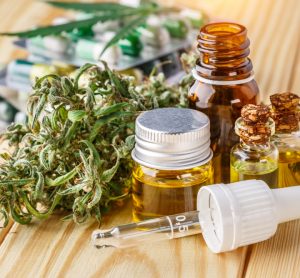 Green leaves of medicinal cannabis with vials of extract oil, tablets in blister packages and a cannbis bud - idea of medicinal cannabis