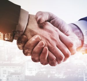 Close up of handshake on city background - idea of mergers and acquisitions