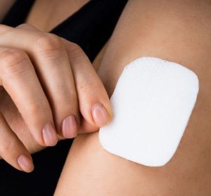 woman applying or removing a microneedle drug patch to her upper arm