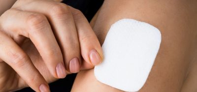 woman applying or removing a microneedle drug patch to her upper arm