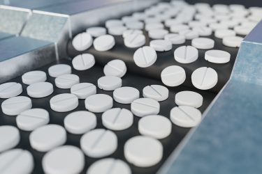 white circular tablets on a conveyor belt