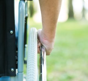 close up image of a man's arm pushing the wheel of his wheelchair