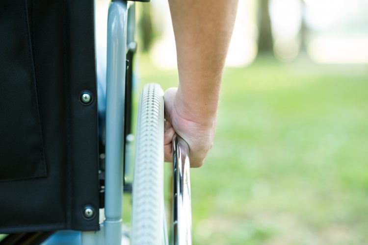 close up image of a man's arm pushing the wheel of his wheelchair