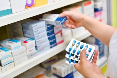 person stacking shelves with boxes of pharmaceuticals