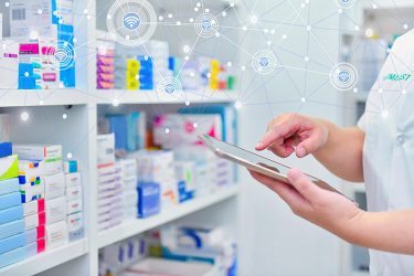 person using a computer tablet in front of a shelf of pharmaceutical packaging - idea of pharmaceutical packaging technology